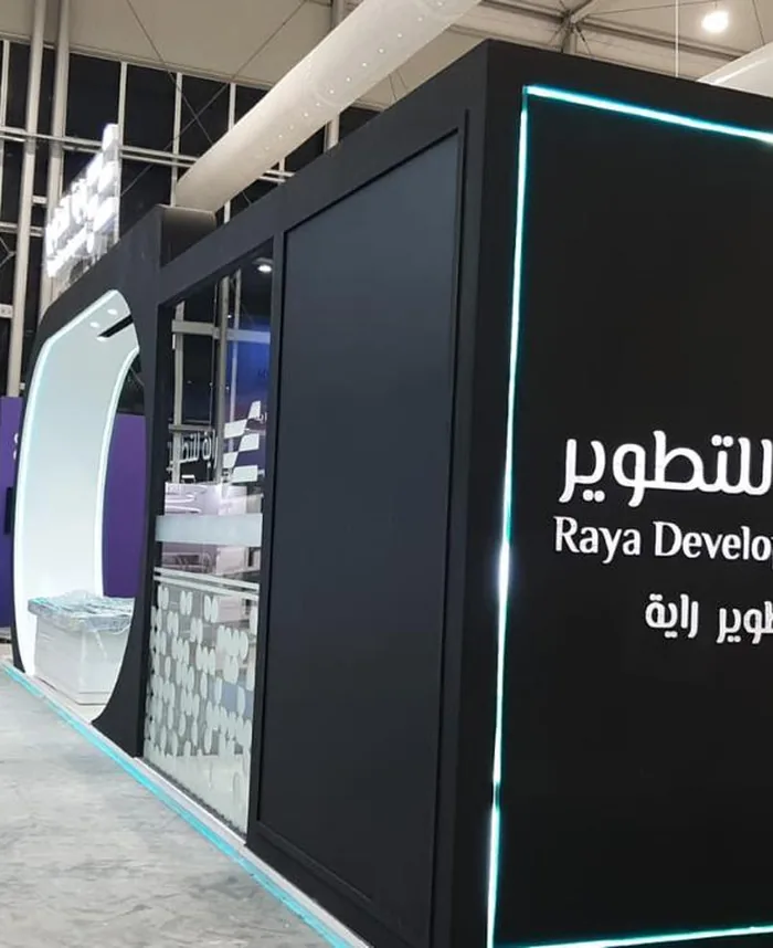Black cube with the lit Raya Development logo at the booth entrance