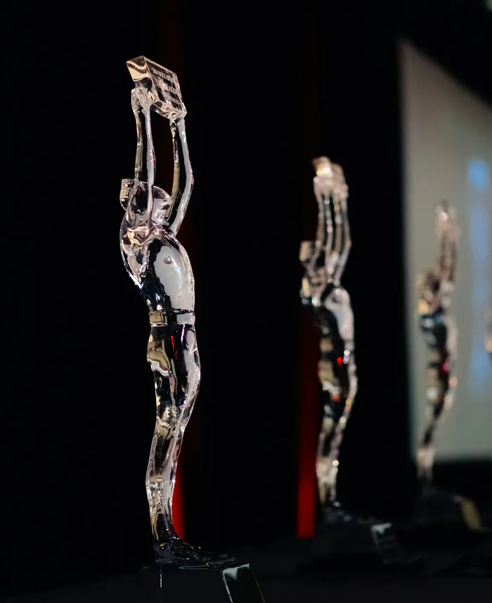 Row of glass award trophies on a dark stage