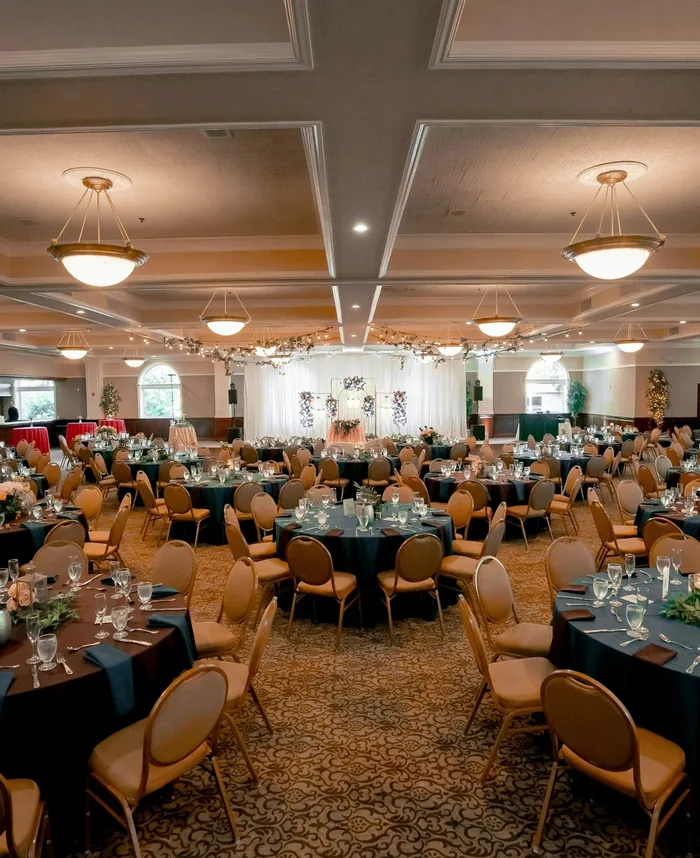 Ballroom set with round tables, teal tablecloths and chandeliers