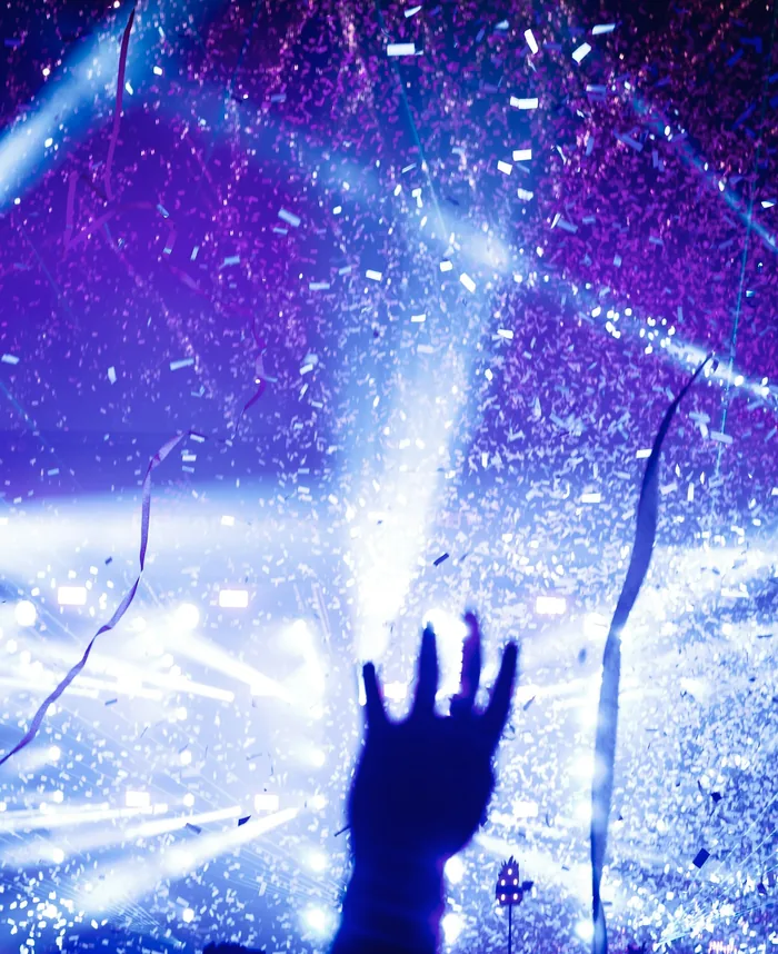Confetti falling through stage lights above a raised hand