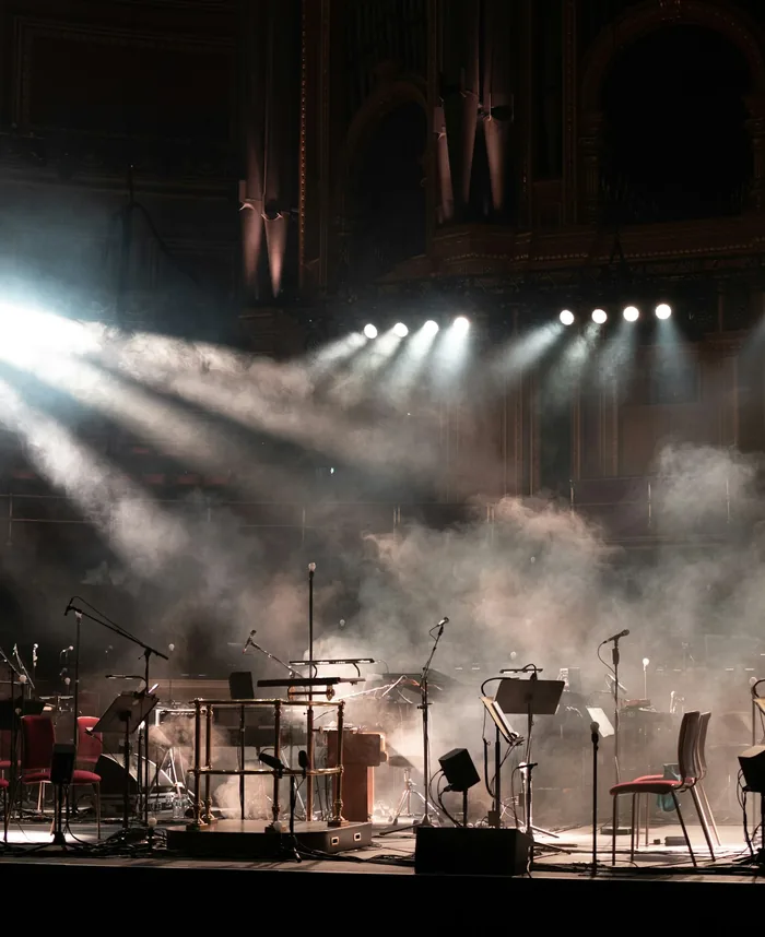 Stage lit by spotlights through haze, set for a live performance
